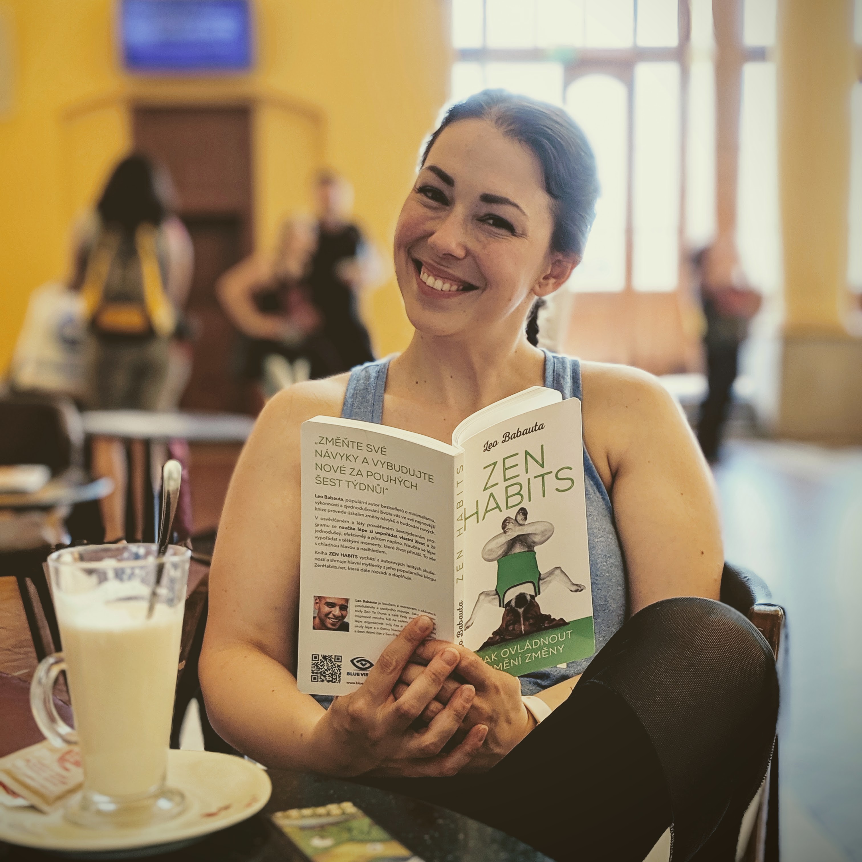 Fotka mě, jak sedím v kavárně na pražském vlakovém nádraží. V ruce držím knížku Zen Habits, kterou si právě čtu.